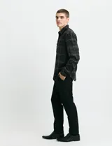 Camisa de franela a cuadros con cuello button-down, manga larga y botones de madera. Presenta dos bolsillos tipo parche en el frente con cierre de botón.