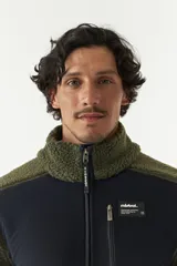 Campera de sherpa con paneles en contraste de color azul marino en el pecho y cuello alto. Cuenta con cierre frontal completo, bolsillos laterales y un bolsillo frontal con cierre, confeccionada en tejido de poliéster.