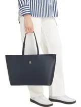 Cartera shopper azul marino de Tommy Hilfiger, confeccionada en poliuretano con doble asa superior y cierre de cremallera. Presenta el logotipo metálico de la marca en la parte delantera.