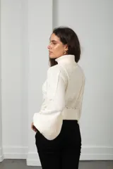 Polera de punto color blanco con cuello alto, mangas globo y diseño de trenzas y calados en el frente.