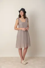 Vestido corto de seda color topo, con escote en V y tirantes anudados en los hombros. Corte suelto y ligero.