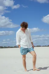 Short de baño celeste con estampado de hojas de palmera en blanco.