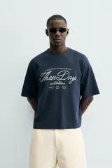 Camiseta de manga corta, cuello redondo y calce relajado, confeccionada en tejido con estructura waffle de color azul marino. Presenta estampados y bordados combinados a contraste en el delantero con texto en blanco.