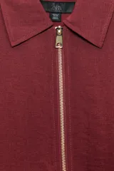 Cazadora tipo bomber color marrón, confeccionada en mezcla de viscosa. Tiene cuello solapa, manga larga, bolsillos de vivo en los laterales y bajo acabado en elástico. Cierre frontal con cremallera metálica.