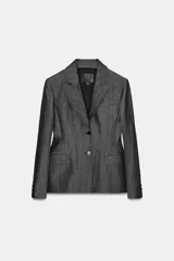 Blazer de mujer color gris oscuro, con efecto denim o tejido texturizado. Presenta cuello solapa de muescas, hombreras, bolsillos con solapa en el delantero y cierre frontal de dos botones oscuros.