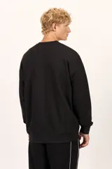 Buzo Billabong Arch Over Crew de color negro, con cuello redondo y diseño de mangas caídas. Presenta un pequeño bordado en hilo blanco en el centro del pecho con el nombre de la marca en tipografía arqueada.