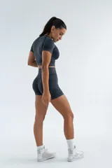 Remera deportiva verde oliva de corte cropped, con cuello redondo y mangas cortas.