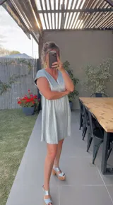 Vestido corto plateado con escote en V y mangas cortas.