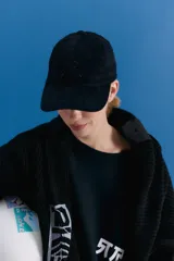 Gorra tipo cap confeccionada en corderoy negro, con isologo bordado a tono en el frente y tira de ajuste con hebilla metálica en la parte posterior.