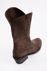Bota de caña media estilo western, confeccionada en cuero vacuno con acabado de gamuza en color marrón, con taco cuadrado y puntera redondeada.