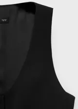 Chaleco negro de corte recto y estilo sastre, con cuello redondo abierto, tirantes anchos y cierre frontal de botones. Cuenta con forro interior completo.