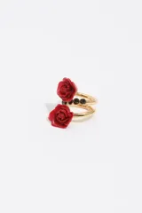 Anillo en espiral de metal dorado con diseño de dos rosas rojas de resina y detalles de cristales negros en el centro.