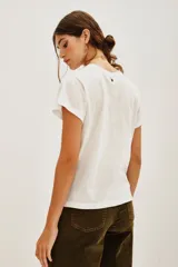 Remera blanca de algodón con estampado frontal de manos en posición de rezo rodeando un corazón rojo con rayos dorados.