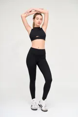 Top deportivo negro con escote alto, abertura en el centro del pecho y ribete blanco en sisas y cuello.