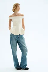 Top en punto tupido de color blanco marfil, con escote off-the-shoulder y diseño ajustado con corte peplum acampanado en la parte inferior.