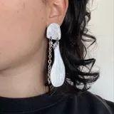 Aros colgantes plateados con diseño geométrico y textura brillante.