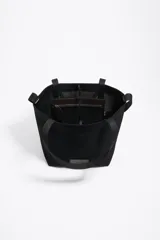 Bolso shopper de estructura blanda confeccionado en tejido de malla técnica negra. Cuenta con doble asa de hombro, cierre mediante cordón ajustable y etiqueta frontal con el logo de la marca Bimba y Lola.