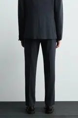 Pantalón de traje corte slim fit, color azul marino con textura sutil. Cuenta con bolsillos laterales, bolsillos traseros con botón y cierre frontal con cremallera y botón.