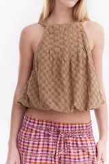 Blusa crop estilo halter con diseño abullonado en la parte inferior, confeccionada en lino con estampado de rayas verticales sutiles.