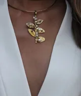 Gargantilla dorada con dije colgante de hojas y perlas.