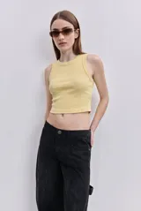 Top crop de calce al cuerpo, confeccionado en algodón con elasticidad, de color amarillo, sin mangas, con escote redondo y terminaciones simples.