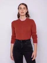 Polera de punto color ladrillo, con cuello alto y puños con detalle en rosa.