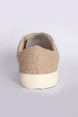 Zapatillas casuales color mostaza con cordones negros y suela blanca.