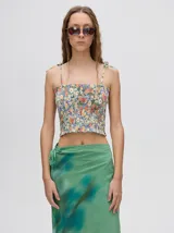 Top crop de tela denim con efecto fruncido, breteles finos ajustables con lazos y diseño entallado al cuerpo.