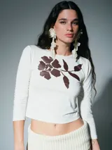 Remera de algodón color crudo con estampa floral en color marrón oscuro, de corte ajustado y manga larga.