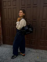 Cartera de hombro confeccionada en cuero y gamuza con diseño de damero, combinando paneles de texturas lisas y aterciopeladas. Presenta una manija trenzada y detalles de costuras artesanales en los laterales.