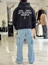 Hoodie de corte boxy fit en color negro, con capucha y estampa en la espalda con texto en blanco que dice 'Community of talented people' junto con un pequeño logotipo y el texto 'creative studio'.