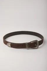 Cinturón de cuero gamuzado color marrón chocolate con hebilla, pasador y puntera de metal plateado con detalles grabados estilo western.