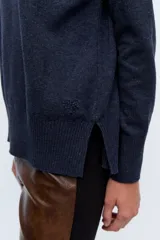 Polera tejida de punto confeccionada en lambswool color gris claro, con cuello alto y calce holgado.