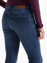 Jeans de mezclilla azul oscuro, tiro medio, con calce ajustado en cadera y muslos, y bota ancha acampanada.