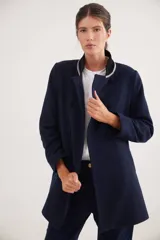 Tapado corto de paño de lana, color azul marino, con cuello mao en pana negra y detalles de cinta de terciopelo. Presenta cierre frontal con botones forrados, cortes entallados y bolsillos delanteros.