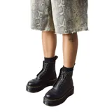 Botas Dr. Martens modelo Sinclair, confeccionadas en cuero Milled Nappa de textura granulada. Presentan una suela Quad con plataforma y cámara de aire, pespuntes amarillos característicos y un cierre frontal extraíble sobre los cordones.