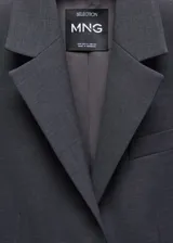 Body con diseño de blazer entallado, confeccionado en tejido mezcla de lana. Presenta cuello con solapas de muesca, cierre frontal con botones, manga larga y detalle de pinzas delanteras y traseras.