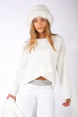 Sweater de corte asimétrico y diseño cruzado en el frente, con cuello redondo y mangas largas holgadas, en color crudo.