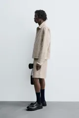 Sobrecamisa de hombre con corte relajado, confeccionada en tejido texturizado jaspeado en tonos beige y negro. Presenta cuello solapa, manga larga con puño de botón y cierre frontal de botonadura.