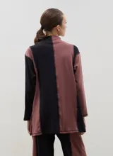 Polera de algodón con diseño bicolor en paneles verticales negros y bordó, cuello alto y tajos laterales.