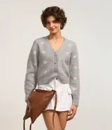 Cardigan corto gris con estampado de corazones rosas, escote en V y cierre abotonado.