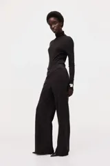 Pantalón de punto pesado color negro, de corte recto y acabado cepillado suave, con elástico revestido en la cintura y bolsillos parche delanteros con botón.