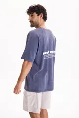 Remera de manga corta raglán con lavado acid wash color azul, de corte holgado, cuello redondo y estampa tipográfica en la espalda.