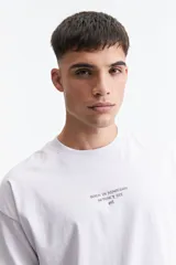 Remera gris de manga corta con corte boxy y estampado en la espalda con una rosa y texto en forma circular.