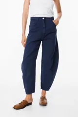 Jean de corte balloon en color azul marino, con cintura alta, cierre frontal con botón y bolsillos laterales. Presenta costuras laterales curvadas que definen su silueta amplia y relajada.