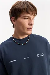 Remera oversize de color azul marino, de manga corta y cuello redondo. Presenta un diseño estampado en la espalda con la inscripción "Boundless Art", un gráfico circular abstracto y textos adicionales.