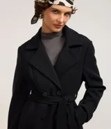 Saco negro confeccionado en polivelour con cuello solapa, doble botonadura frontal, bolsillos y cinturón para lazo en la cintura.