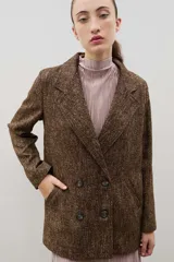 Blazer de lana con diseño bicolor, cuerpo en color negro y mangas en color crema. Presenta un corte holgado, cierre cruzado con doble botonadura y solapas amplias en contraste.