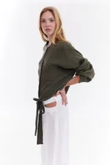 Camisa blanca de lino italiano, de corte holgado, mangas largas abullonadas, cuello mao y cierre frontal con botones, con diseño para anudar en la cintura.