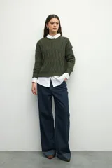 Sweater de tejido tramado en color verde oliva, con cuello redondo y mangas largas. Presenta un diseño de textura acanalada vertical.